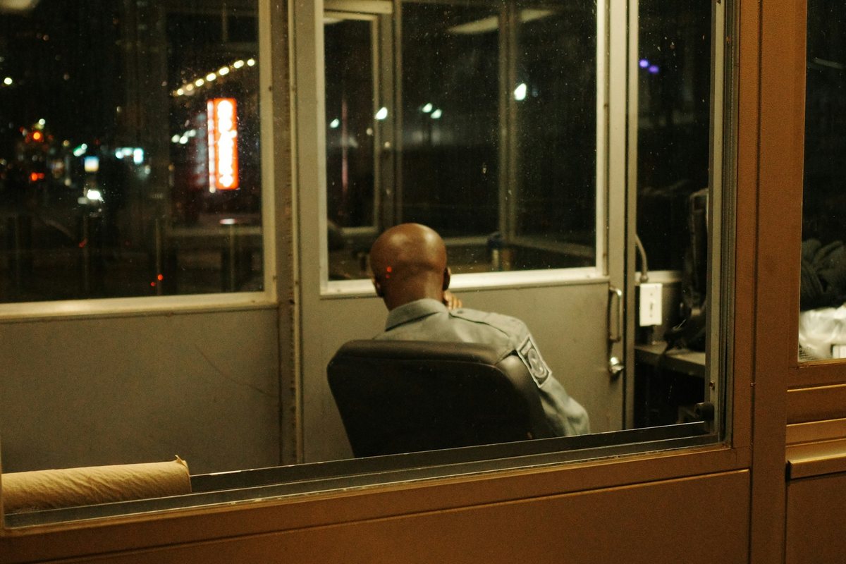 Guardia de turno dentro de la caseta, de noche, visto de espaldas